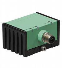 Caméra industrielle de forme rectangulaire avec un boîtier vert et une base noire. Elle dispose d'un raccordement circulaire à l'avant dans un environnement industriel.