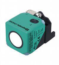 Un capteur carré de couleur turquoise avec un support noir, de 'Pepperl+Fuchs', détecte la distance ou le mouvement.