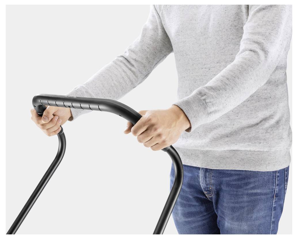 Une personne portant un pull gris pousse une tondeuse à gazon, concentrée sur la poignée noire.