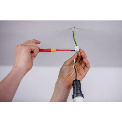 Une personne installe un luminaire de plafond. Une main tient un tournevis, tandis que l'autre connecte des fils.
