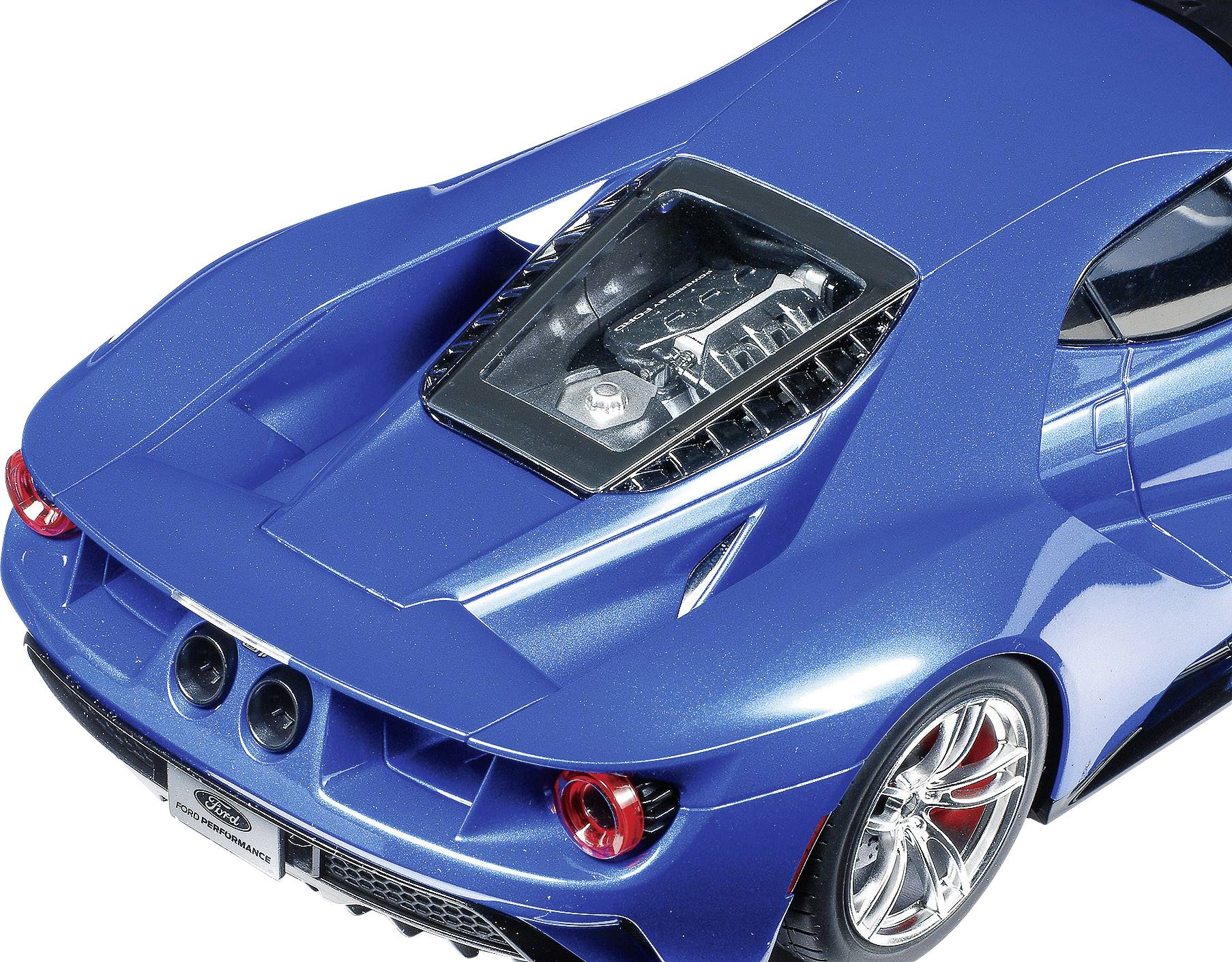 Une voiture de sport bleue vue de dessus. Le moteur est visible à travers un couvercle transparent, avec un double échappement et des feux arrière apparents.