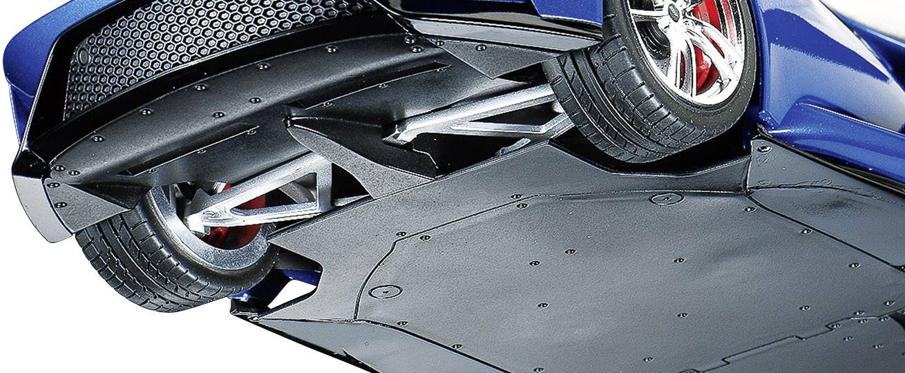 Vue inférieure d'une voiture montrant un design de châssis complexe et une suspension de roue. Couleur du véhicule bleue, jantes argentées, arrière-plan neutre.