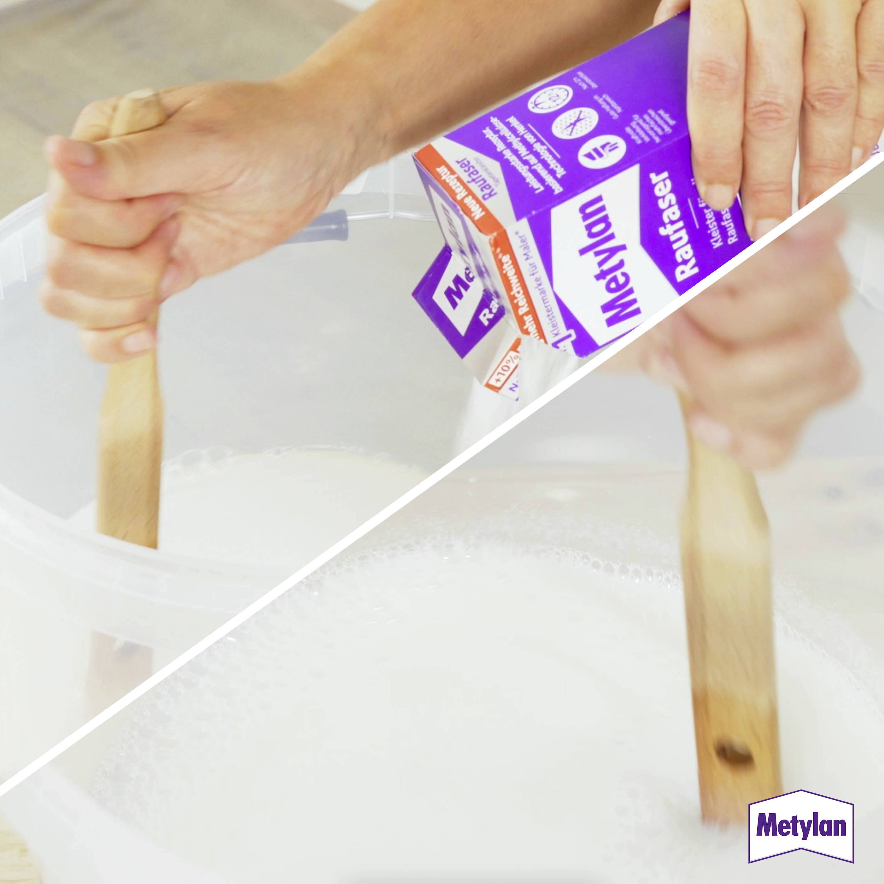 « Une personne mélangeant une pâte blanche dans un récipient avec un bâton en bois, tenant une boîte de produit adhésif Metylan. »