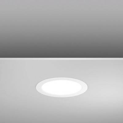 Un luminaire rond encastré dans un plafond lisse et gris brille intensément.