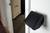 Un lecteur de carte noir est fixé au mur à côté d'une porte ouverte. À l'arrière-plan, on peut voir une pièce avec un sol moquetté.
