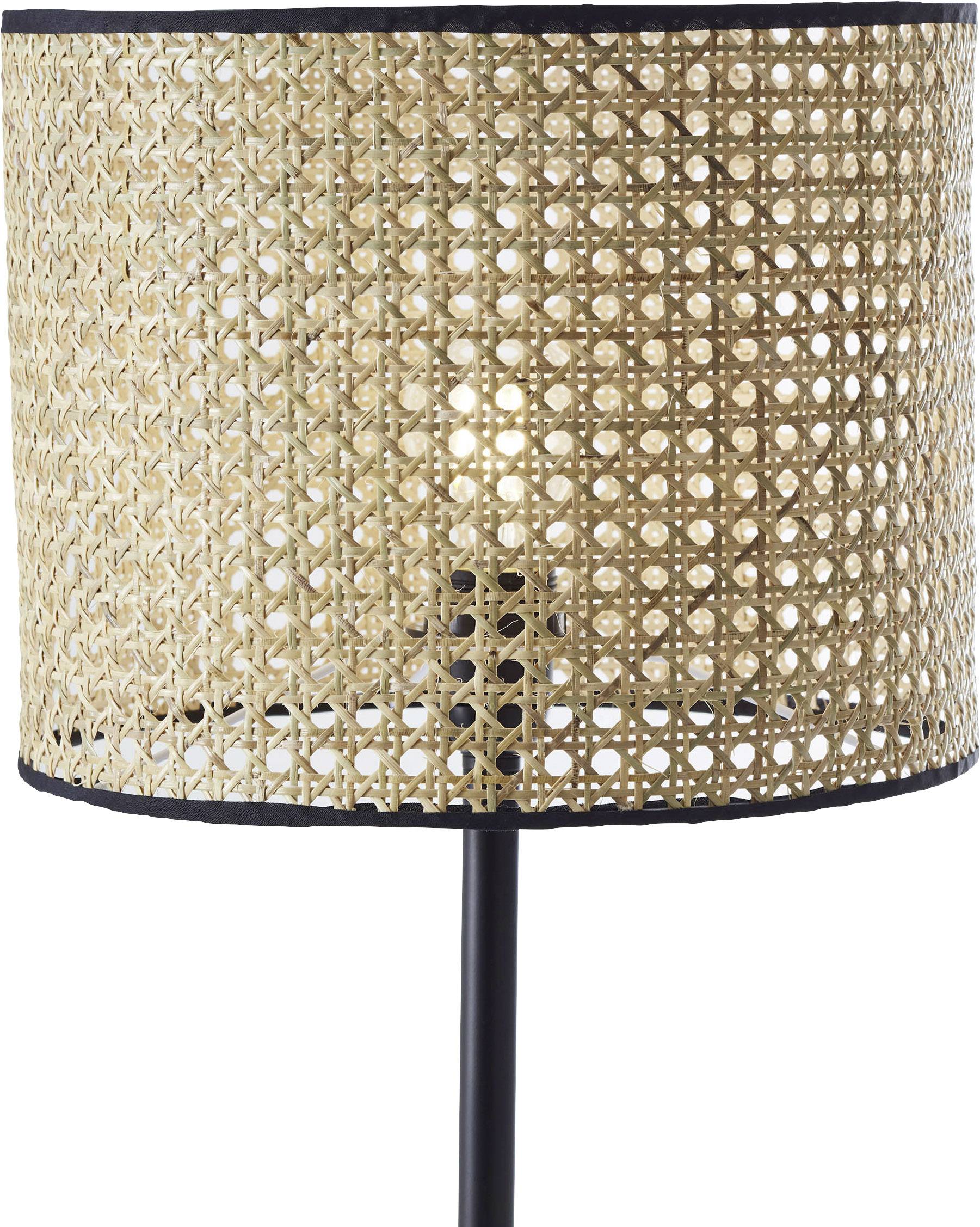 Une lampe sur pied avec un abat-jour cylindrique en rotin tressé, monté sur un socle en métal noir.