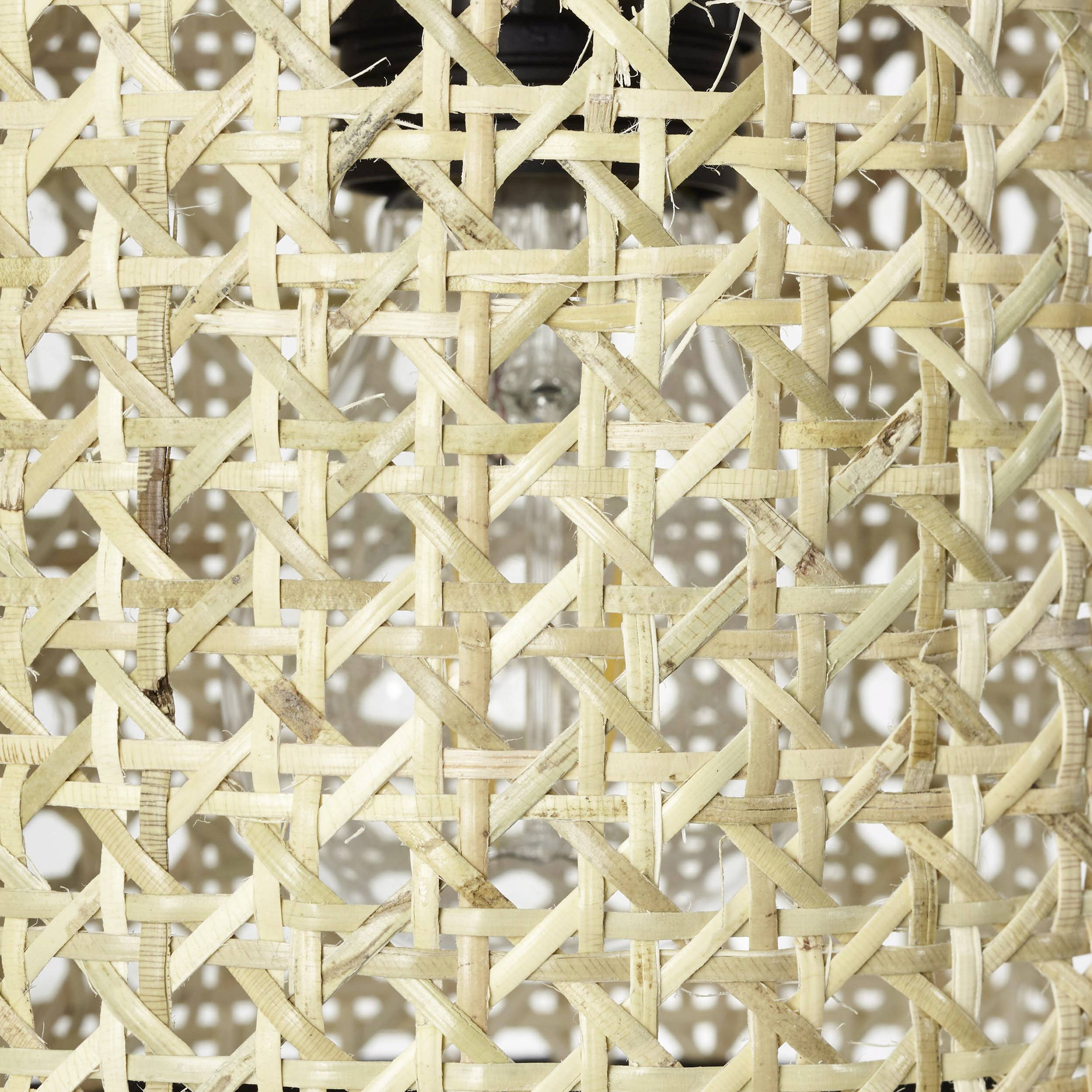 Une structure tressée en fibres de bambou formant un motif rustique. Une ampoule est visible en arrière-plan.
