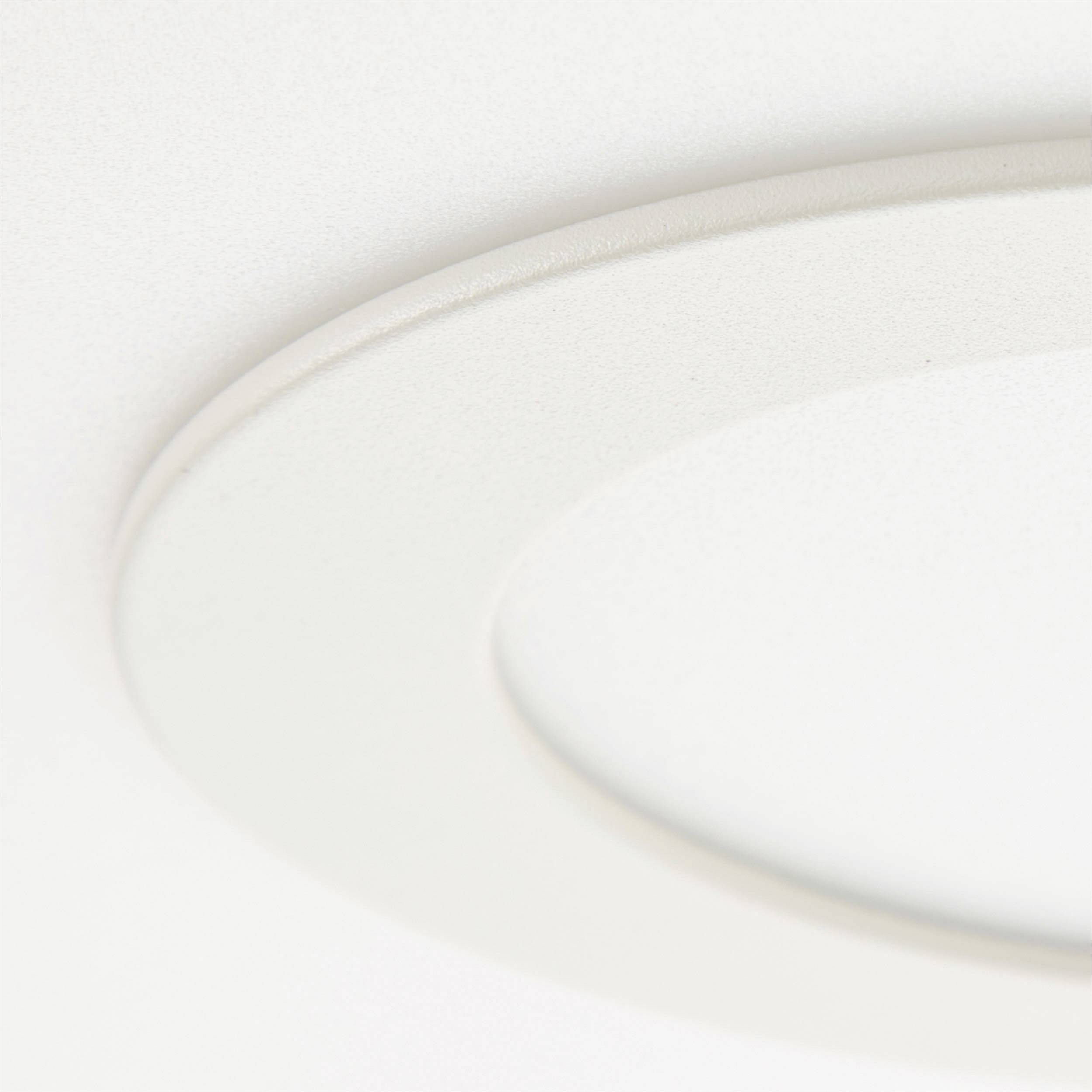 Luminaire de plafond blanc, rond, encastré. Design minimaliste, intégré dans un plafond lisse.