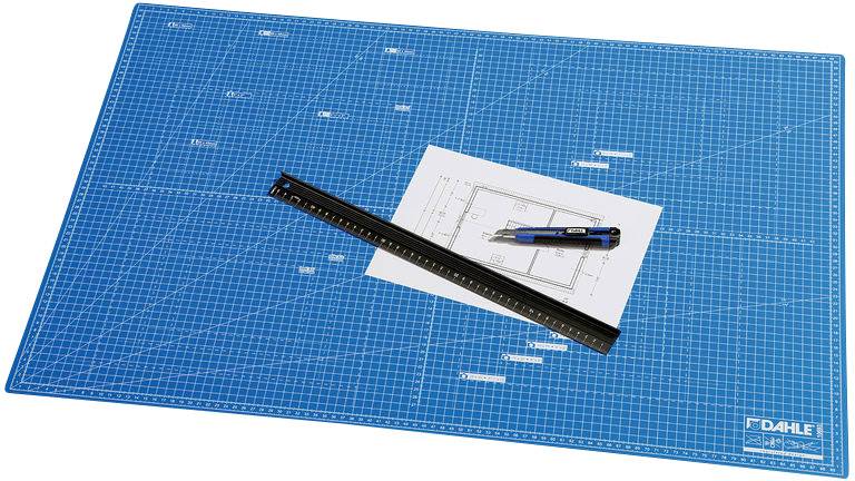 Un tapis de coupe bleu avec une grille en millimètres, sur lequel sont posés une règle, un plan d'architecture et un cutter.