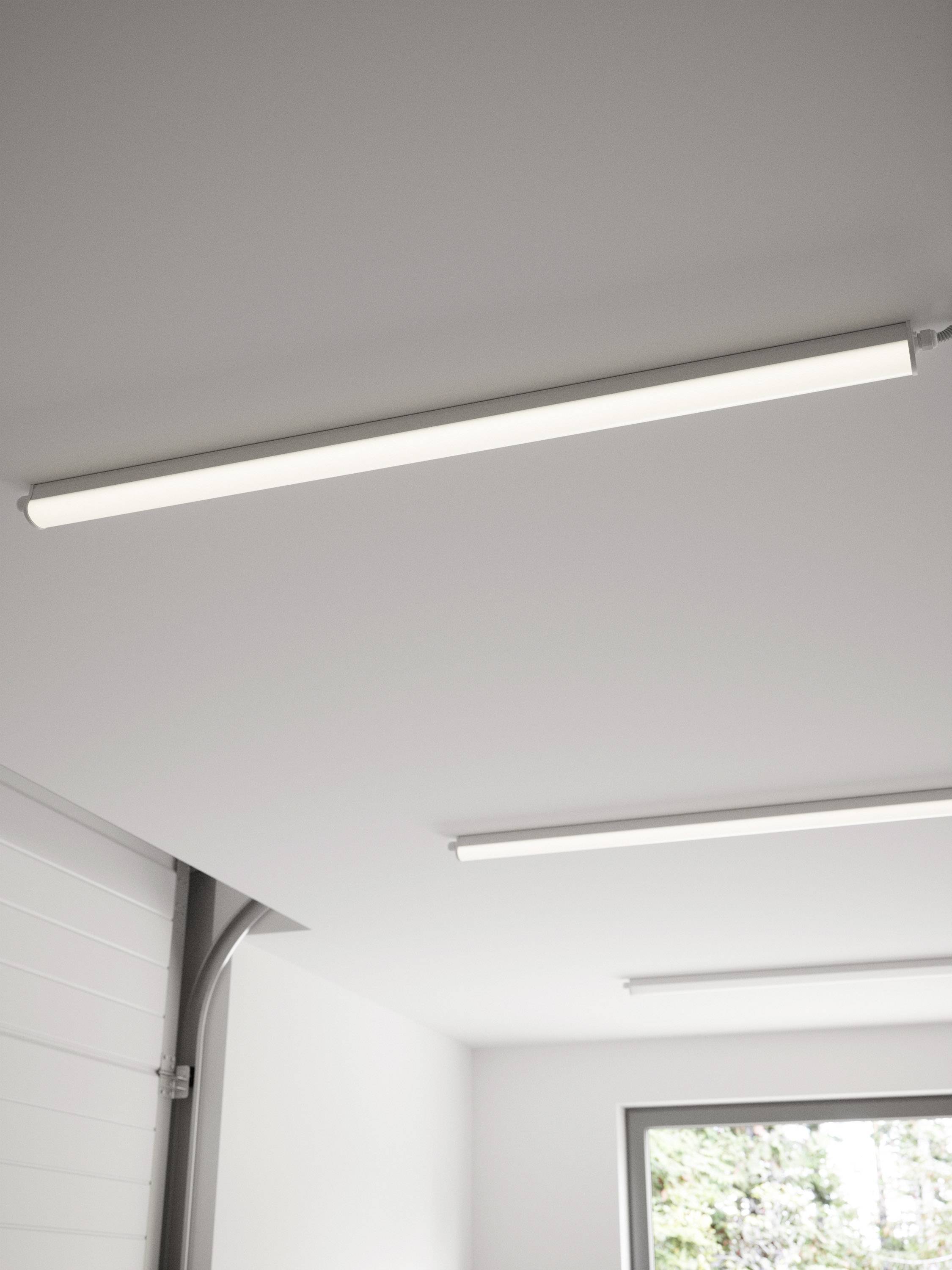 Deux luminaires de plafond LED rectangulaires dans une pièce aménagée de manière minimaliste, avec une grande fenêtre et une porte de garage.
