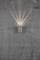 Applique murale sur un mur gris projetant de la lumière vers le haut et le bas, créant des effets lumineux décoratifs.