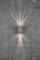Une lampe murale éclaire avec un motif lumineux diffus vers le haut et le bas sur un mur de béton gris et fissuré.