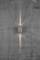 Un applique murale sur un mur gris, projetant de la lumière vers le haut et vers le bas, créant un motif lumineux en forme de croix sur la surface du mur.