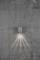 Applique murale sur un mur en béton gris texturé, diffusant une lumière uniforme vers le bas et créant un effet lumineux doux.