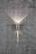 Lampe murale sur un mur en béton, projetant un faisceau lumineux vers le haut et le bas, créant des jeux d'ombres. Éléments d'éclairage décoratifs.