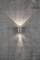 Un luminaire cylindrique fixé à un mur en béton, émettant de la lumière vers le haut et le bas et créant un motif lumineux uniforme.