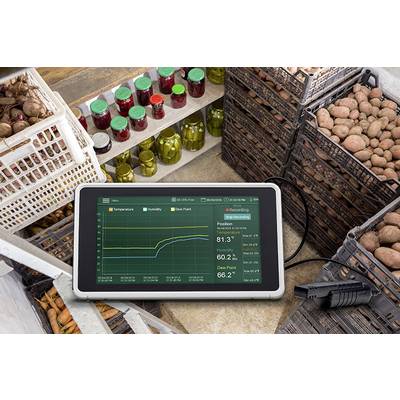Une tablette affiche graphiquement l'évolution de la température et de l'humidité dans un entrepôt de stockage avec des pommes de terre et des légumes marinés sur des étagères.