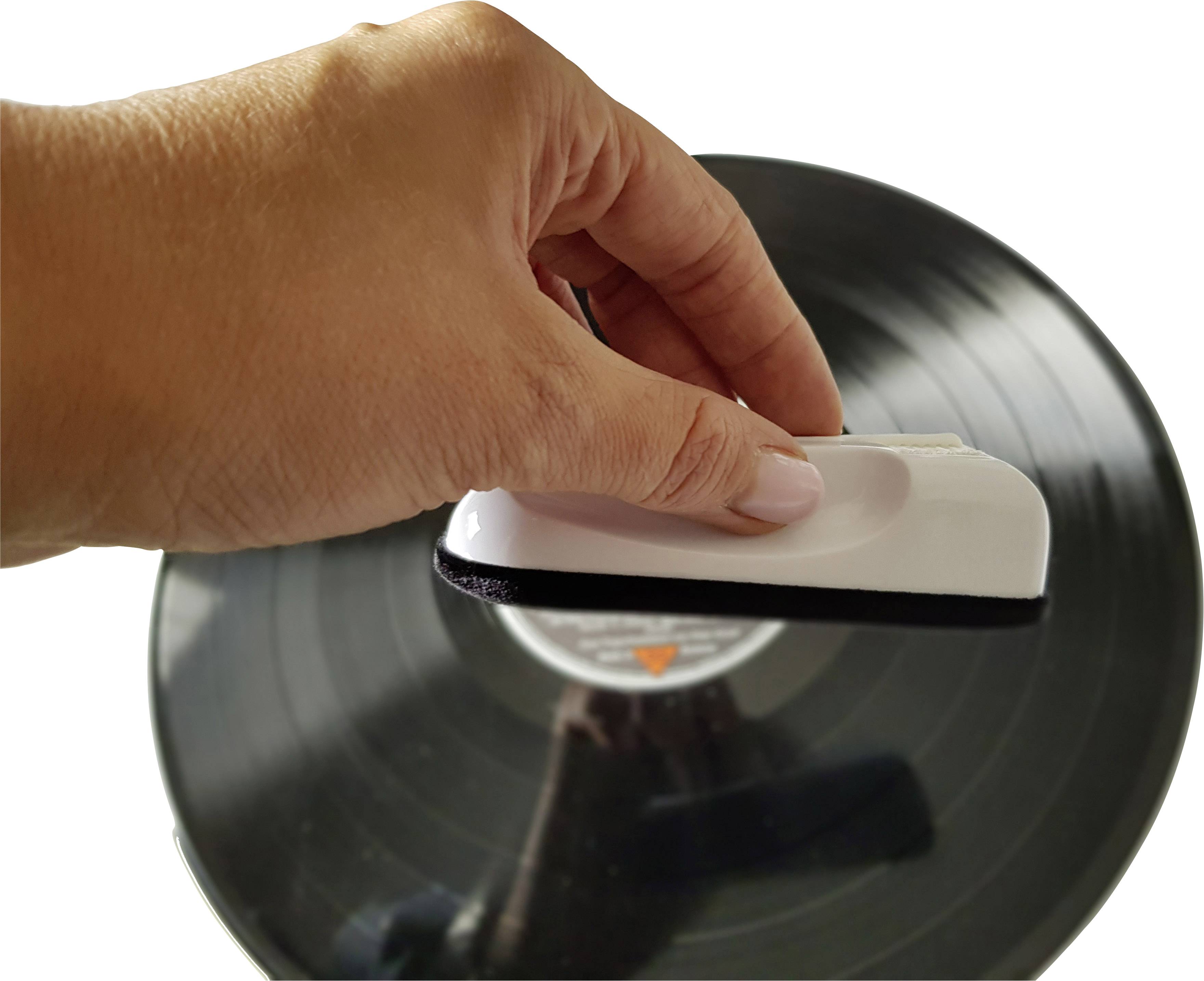 Une main nettoie un disque vinyle avec une brosse blanche.