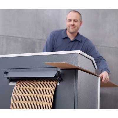 Un homme utilise une machine qui comprime du carton dans une forme déchiquetée.