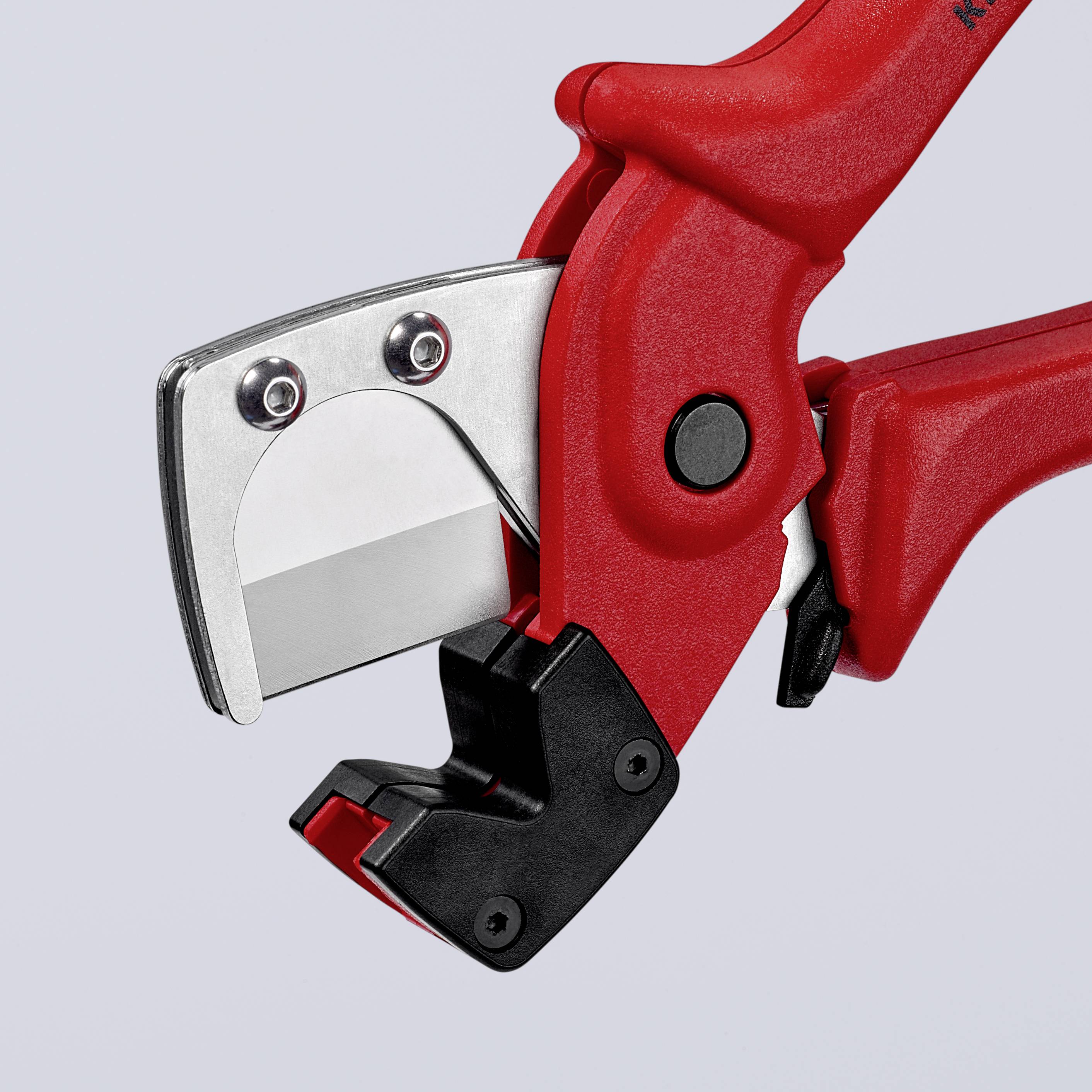 Un outil de coupe rouge avec une lame métallique tranchante, probablement utilisé pour couper précisément des matériaux comme le plastique.