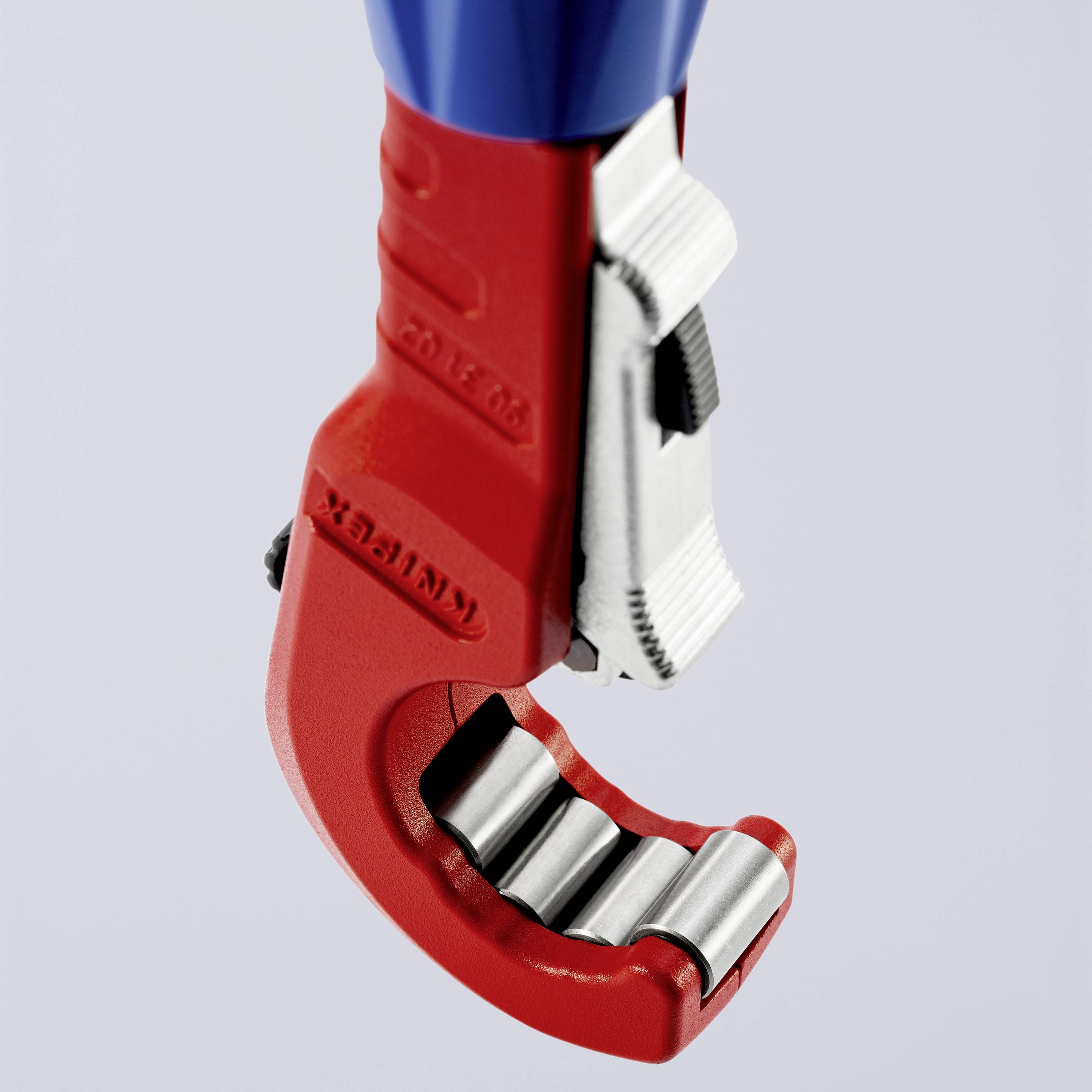 Un outil de coupe de tuyaux rouge avec une poignée bleue et des lames de coupe argentées, adapté pour les tuyaux en cuivre.