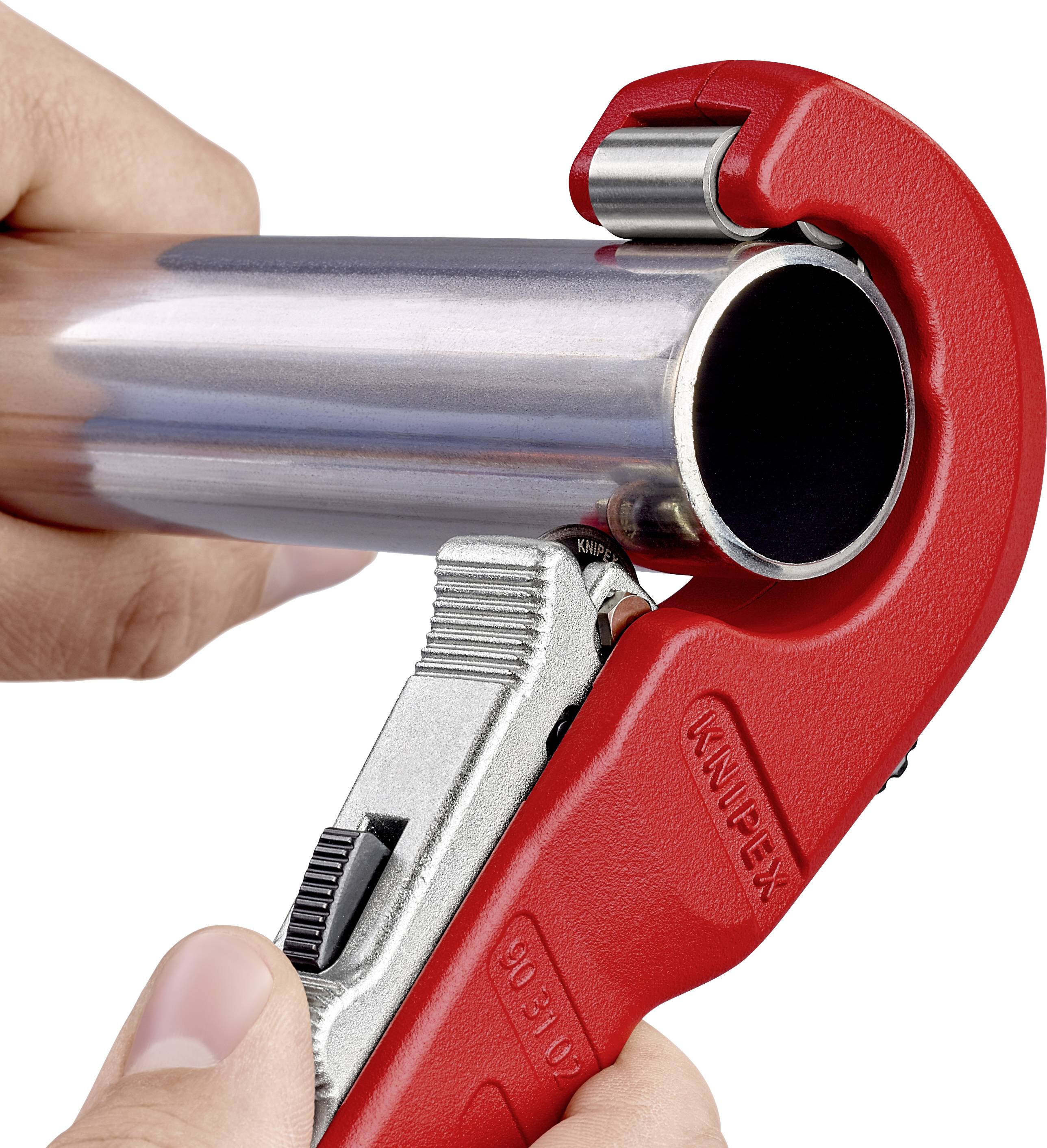 Une main utilise un coupe-tube rouge pour couper un tuyau métallique. Le coupe-tube a une lame argentée et est en position de coupe.