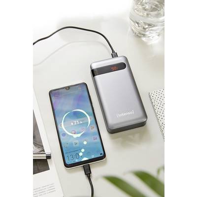 Un smartphone est en train d'être chargé par une batterie externe grise. L'écran du smartphone affiche '71%'. La batterie externe indique '98%'.