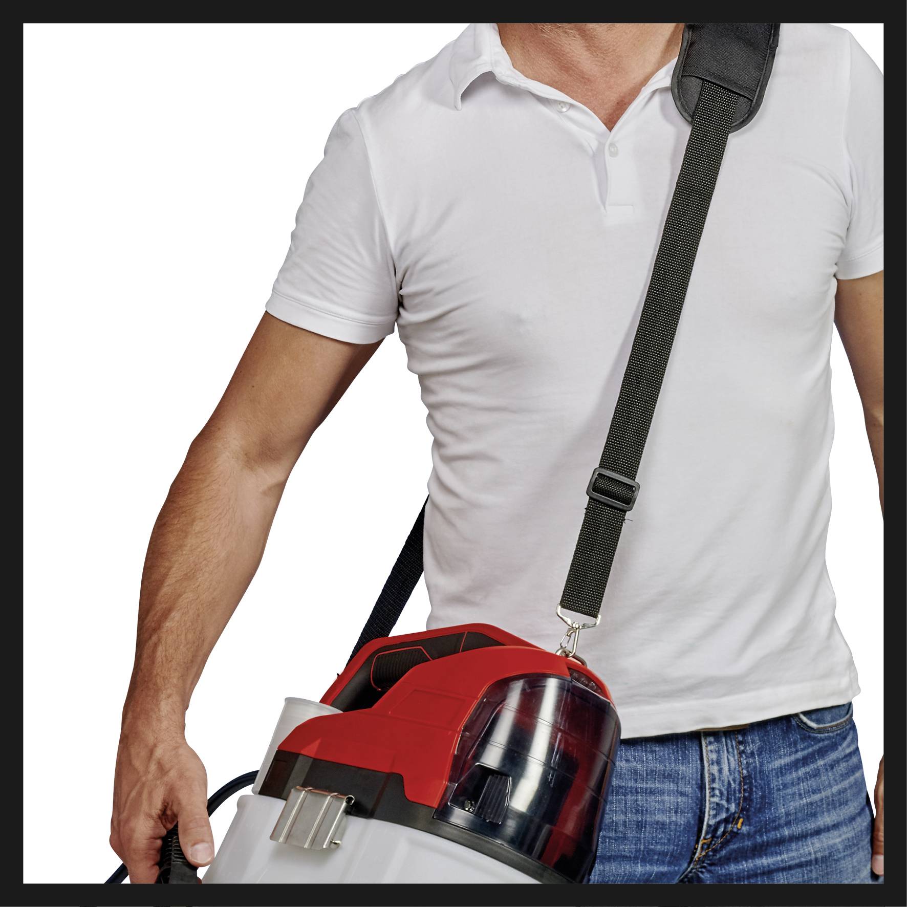 Un homme porte un aspirateur portable rouge et noir avec une bandoulière. Il porte un t-shirt blanc et un jean bleu.