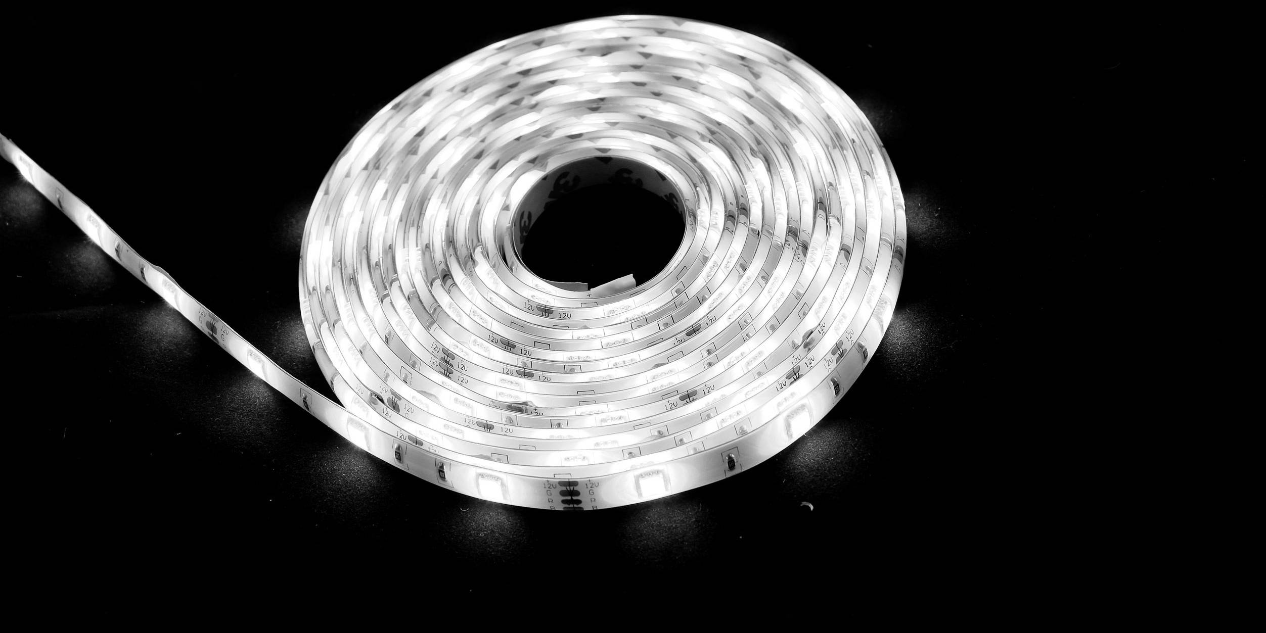 Un ruban de LED blanc enroulé repose sur un fond noir.