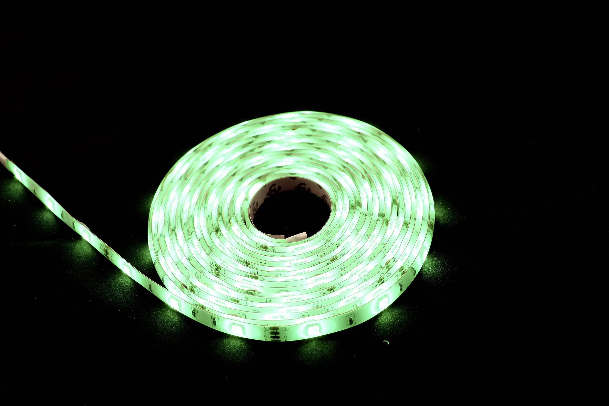 Une guirlande LED verte enroulée brille sur un fond noir.