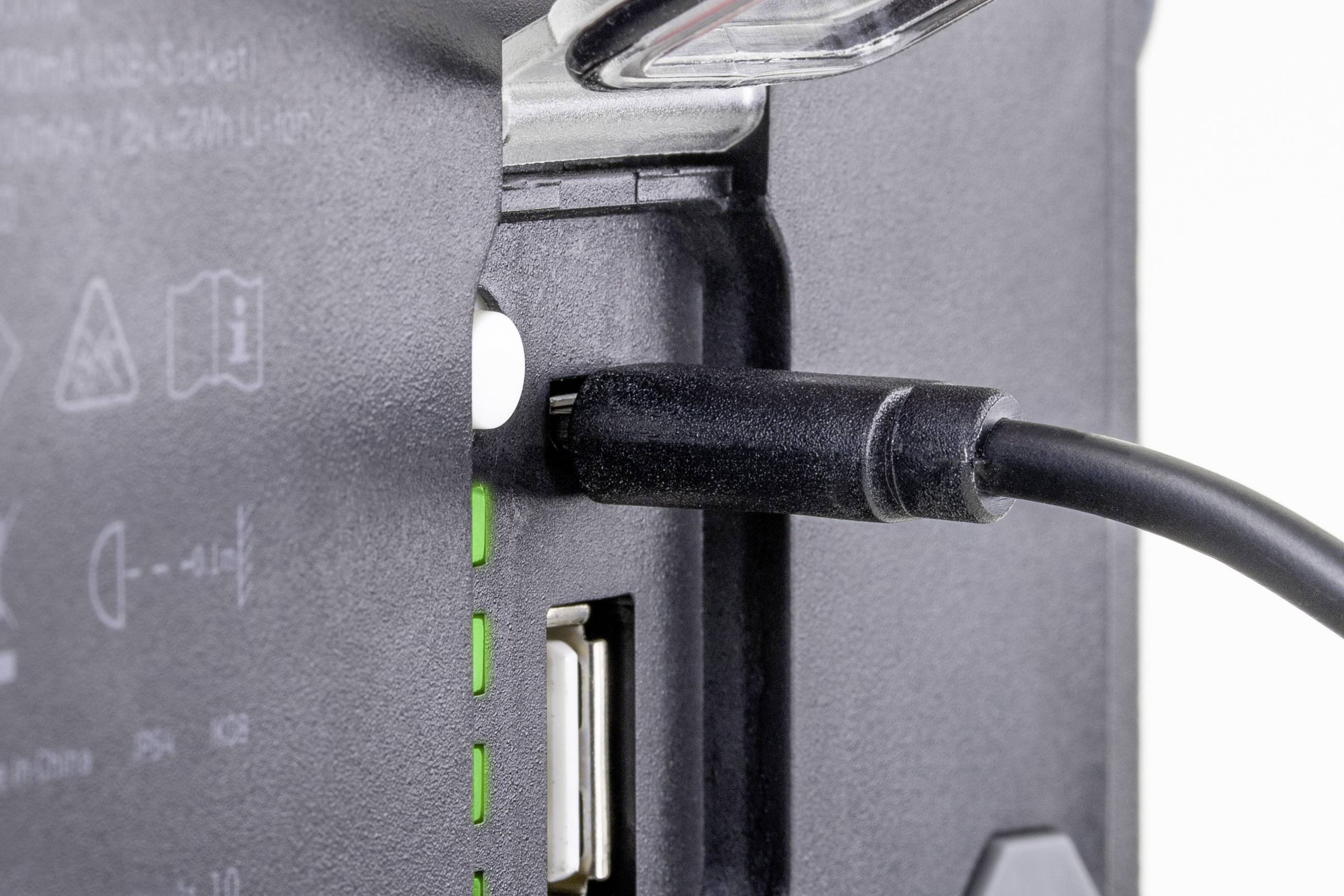 Un câble noir est branché dans un appareil électrique, avec des voyants LED verts qui semblent indiquer le statut de charge.