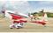 Un avion vintage rouge et blanc sur un terrain d'aviation, prêt au décollage. Un pilote est assis aux commandes. Des collines verdoyantes sont visibles en arrière-plan.