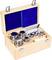 Une boîte en bois ouverte contenant un ensemble de poids métalliques brillants de différentes tailles. L'intérieur de la boîte est tapissé de tissu bleu.