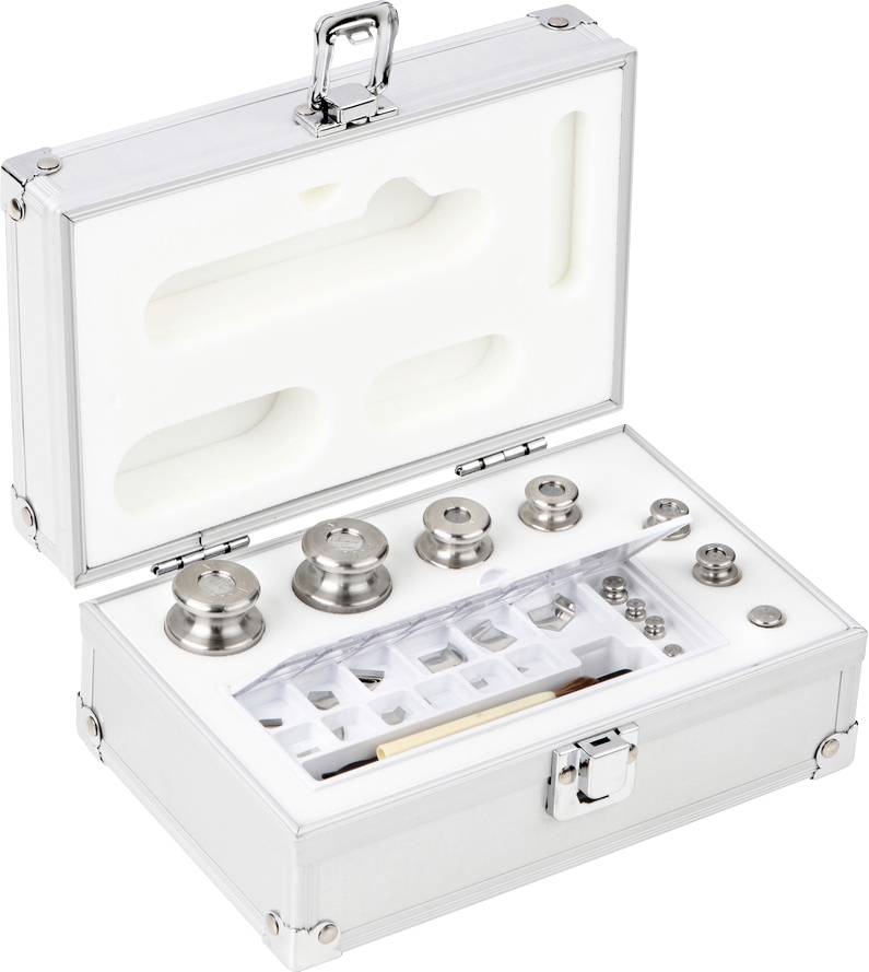 Une valise métallique ouverte contenant différents poids sur un support en mousse, comprenant des formes rondes et cylindriques.