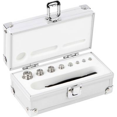 Boîte en argent avec couvercle ouvert montrant plusieurs petits poids métalliques de différentes tailles, disposés sur des insertions en mousse.