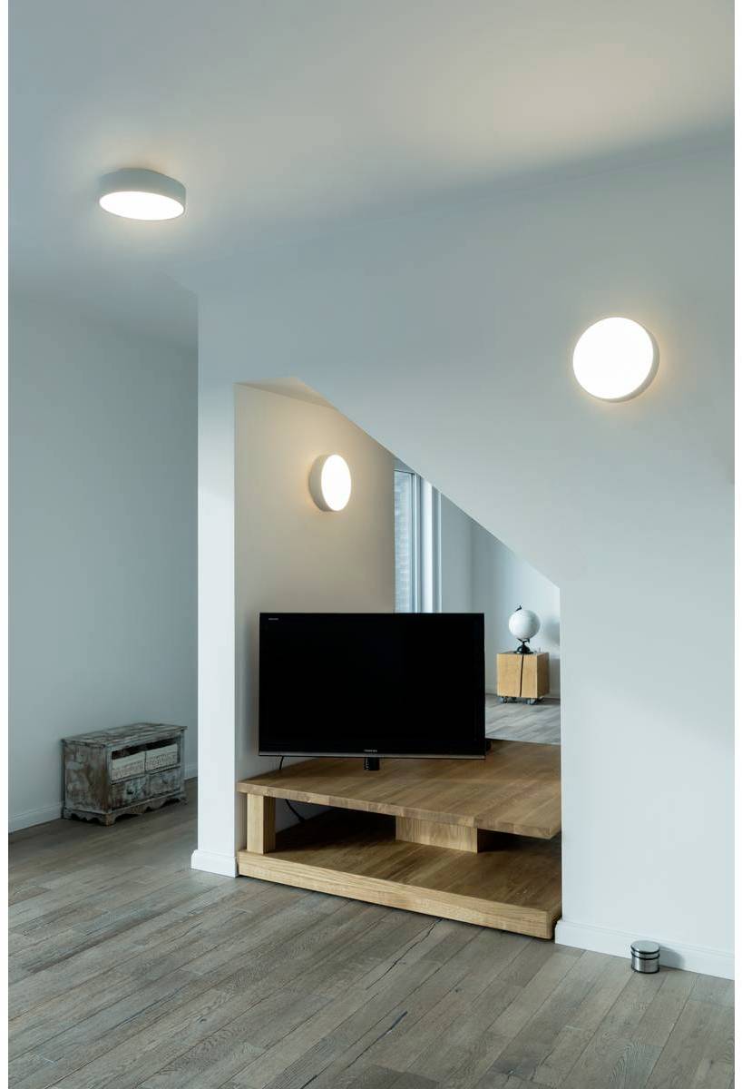 Salon avec un coin télévision au design moderne et minimaliste. Une table en bois supporte la télévision, avec un parquet en bois en dessous.