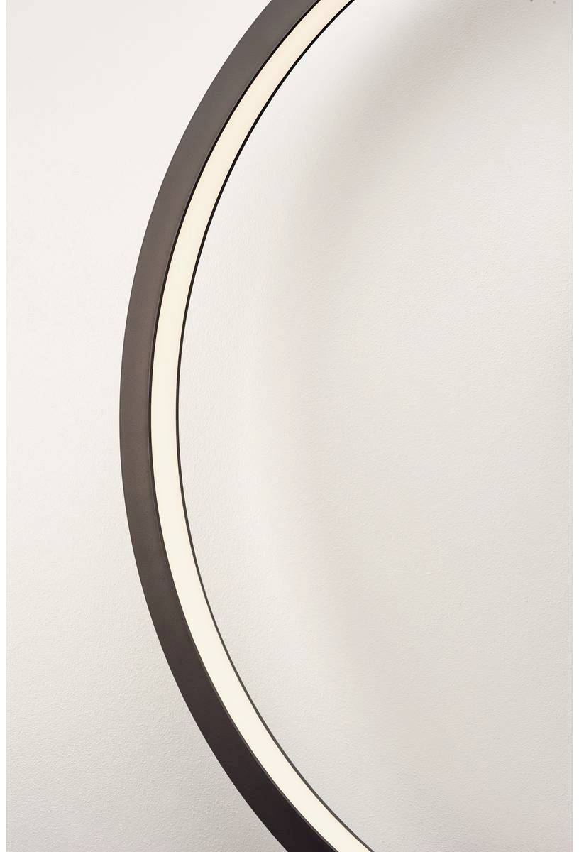 Un extrait d'une sculpture circulaire élégante et éclairée contre un mur blanc.