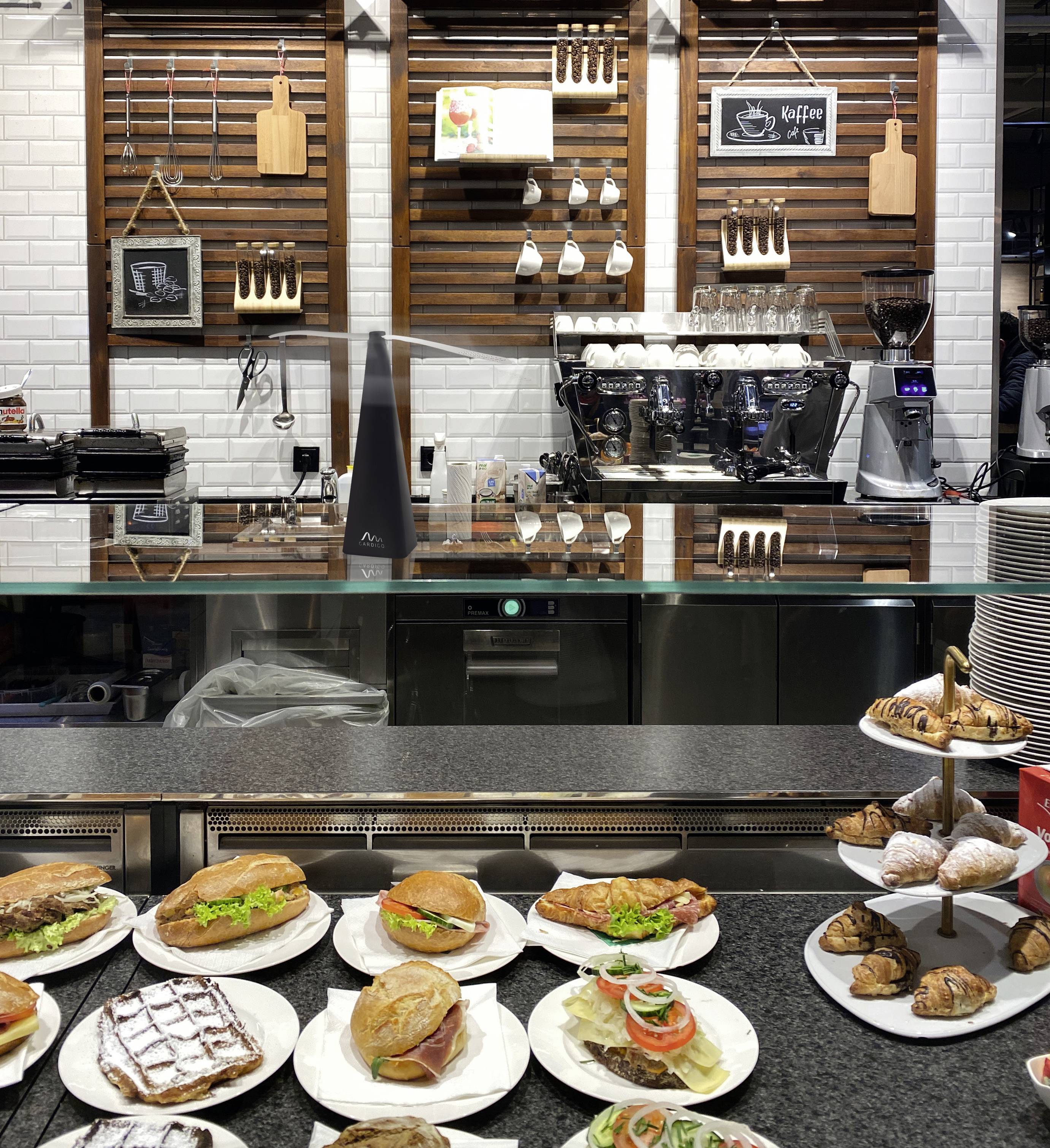 Un comptoir dans un café avec différents sandwichs, croissants et pâtisseries. Une machine à café est placée en arrière-plan.