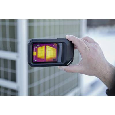 Une main tient une caméra thermique qui capture un refroidisseur d'air. L'écran affiche une répartition thermique avec des différences de température marquées.