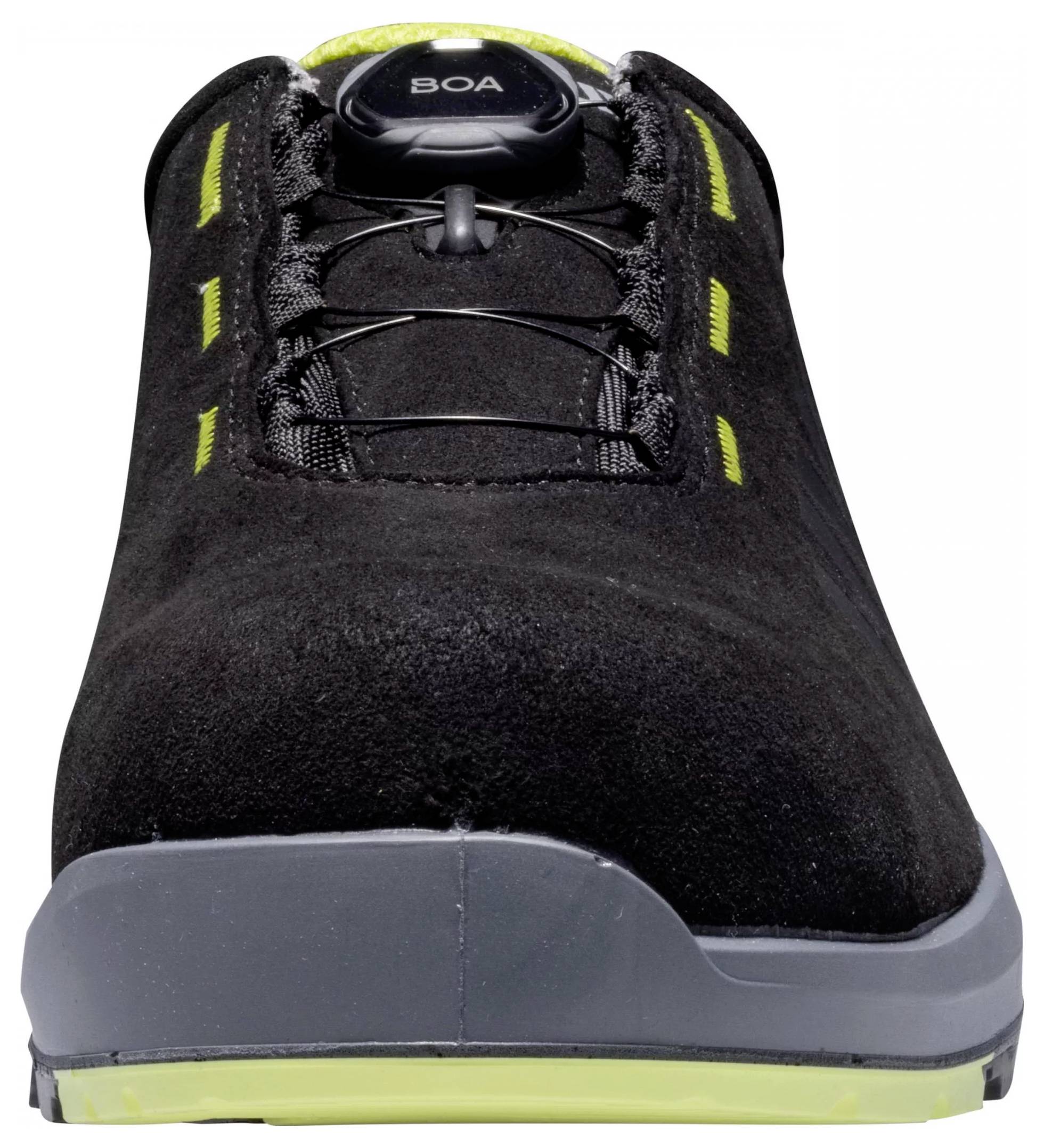 Une chaussure noire avec un système de fermeture à rotation en haut, une semelle grise et des accents jaunes sur les côtés, vue de face.