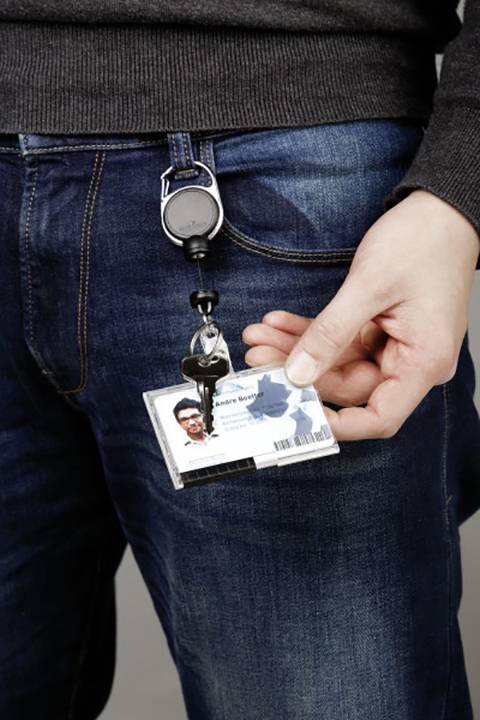 Une personne présente une carte d'identité sur un clip attaché à son jean.
