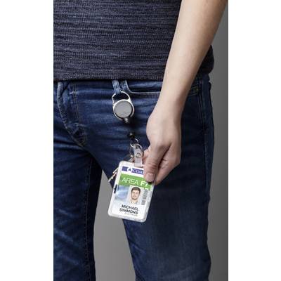 Une personne porte un jean bleu et tient une carte d'identité avec un clip à la main. La carte d'identité montre une photo et le nom 'Michael Simmons'.