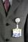 Une personne porte un costume gris avec une cravate rouge, et a une carte d'identité attachée à un clip fixé à la poche de son costume.