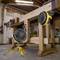 Deux ventilateurs jaunes placés sur une table en bois dans un atelier. Des outils sont visibles en arrière-plan.