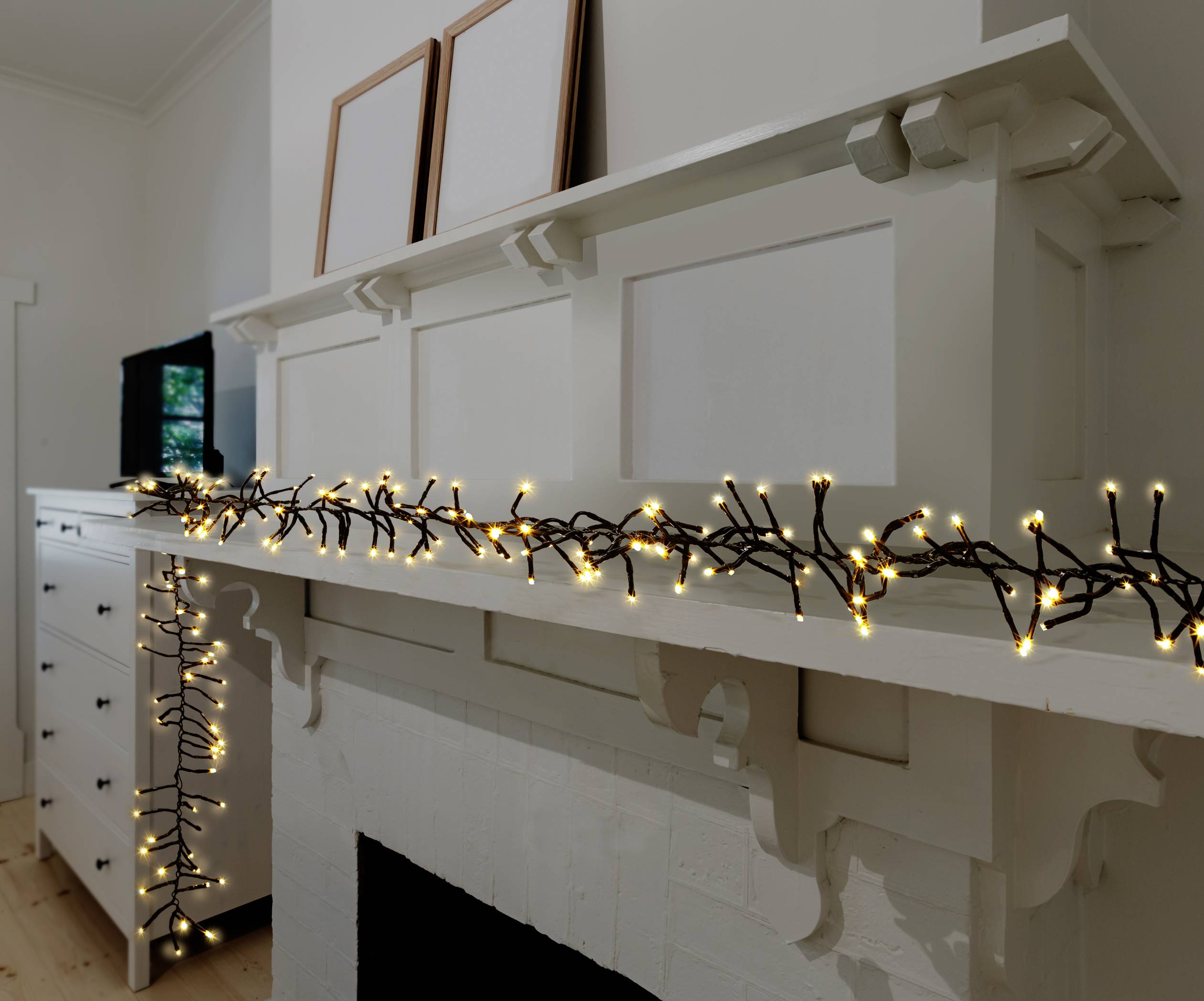 Une étagère de cheminée décorée d'une guirlande lumineuse. Les lumières sont chaleureuses et jaunes, apportant une ambiance cosy à la pièce.