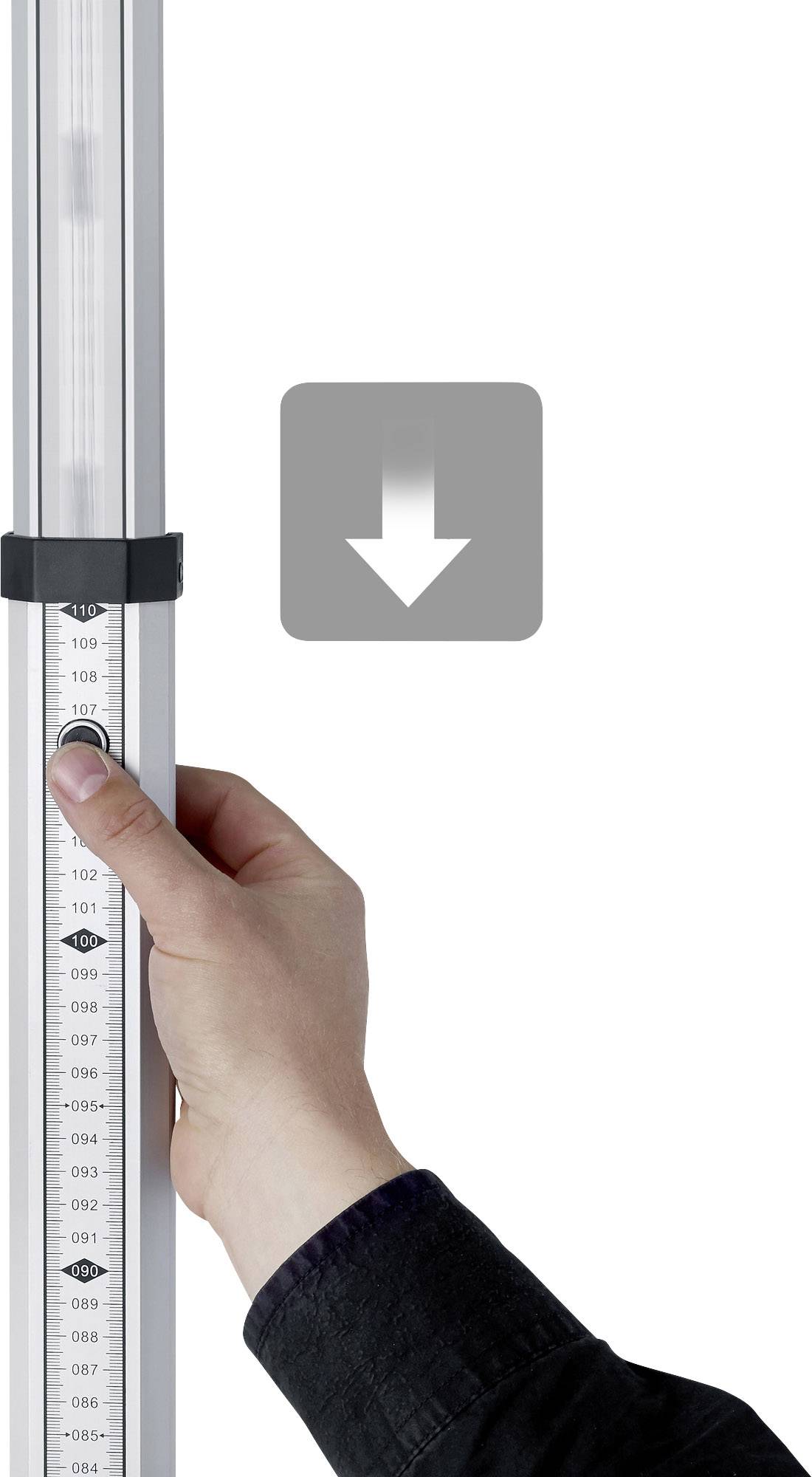 Une main tient un appareil de mesure vertical avec une échelle. Une flèche pointe vers le bas, ce qui suggère un mouvement ou un ajustement.