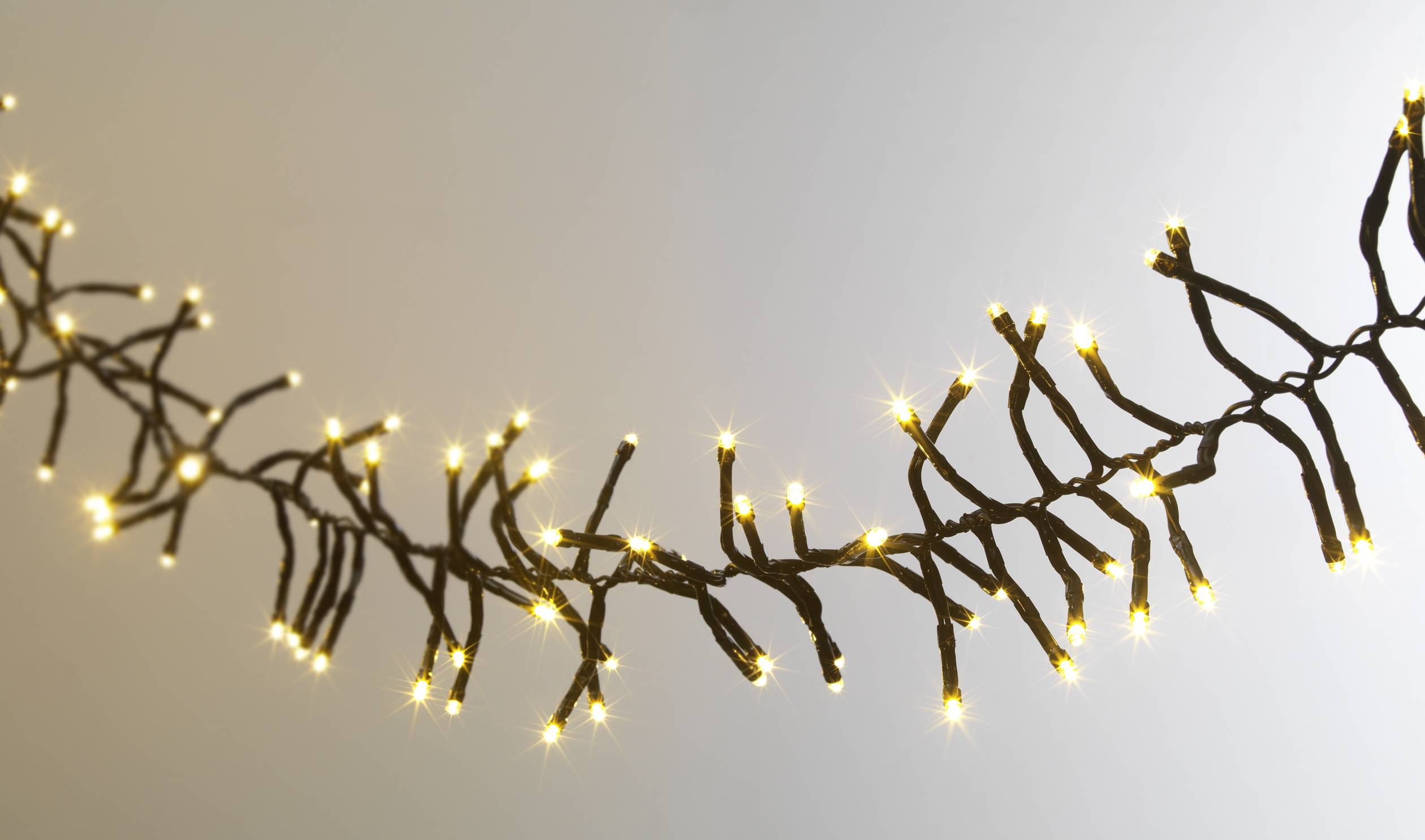 Guirlande lumineuse avec des petites ampoules blanc chaud disposées en zigzag, suspendue devant un fond neutre, créant une ambiance chaleureuse et intime.