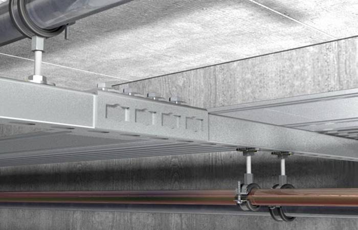 Construction de supports de tuyaux métalliques au plafond, avec des tubes et des fixations apparents ; contexte industriel.