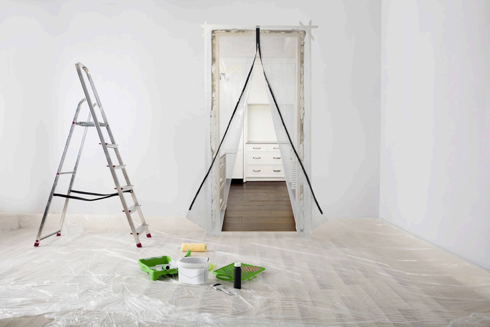 Une échelle et du matériel de peinture sont disposés dans une pièce recouverte de film plastique. Une ouverture de porte recouverte de film mène vers une pièce lumineuse.
