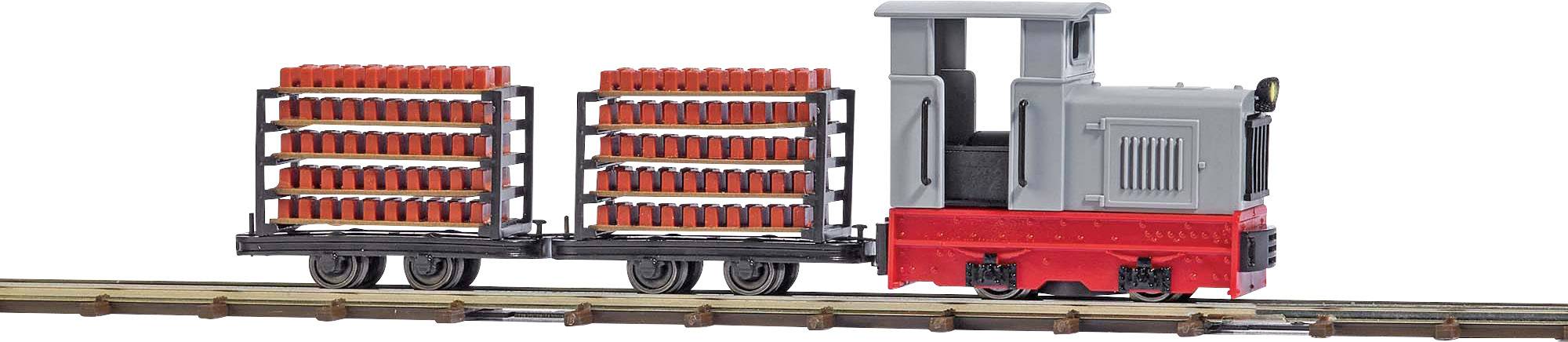 Un train-jouet gris avec des wagons rouges roule sur un rail. Les wagons sont chargés de blocs rouges empilés.